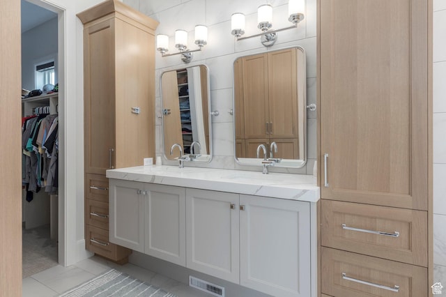 bathroom with a sink, visible vents, a spacious closet, and double vanity