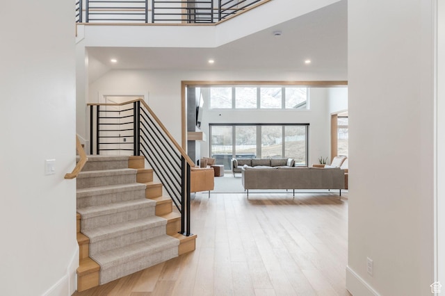 stairway featuring baseboards, a high ceiling, and wood finished floors