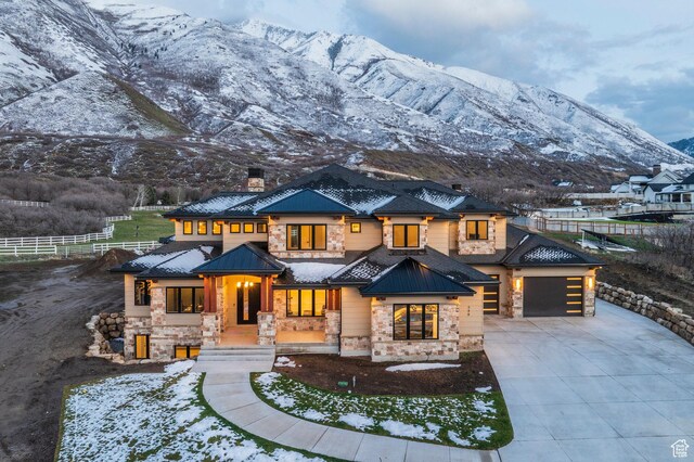 view of front of property featuring a mountain view, a chimney, driveway, stone siding, and an attached garage