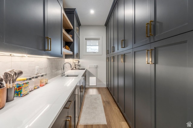 interior space with light wood-type flooring, a sink, baseboards, and recessed lighting