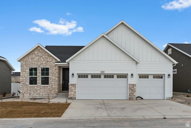 view of front of property featuring driveway, board and batten siding, a garage, and stone siding