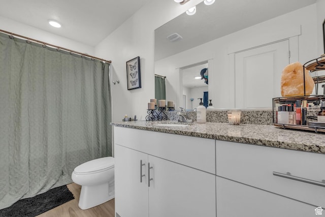 bathroom featuring visible vents, a shower with curtain, toilet, vanity, and wood finished floors
