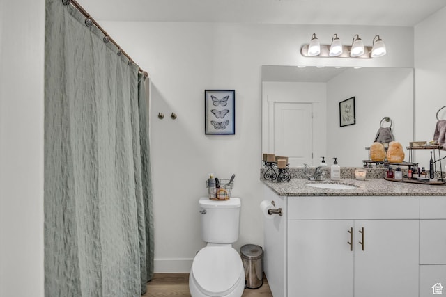 full bath featuring vanity, toilet, curtained shower, wood finished floors, and baseboards