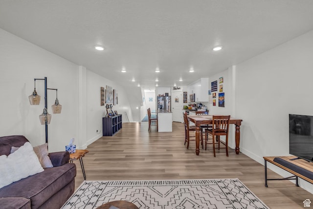 living room featuring recessed lighting, light wood-type flooring, baseboards, and a textured ceiling