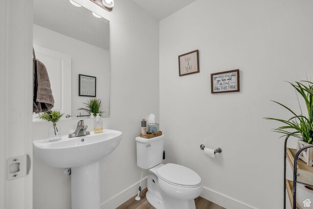 bathroom featuring baseboards, toilet, and wood finished floors