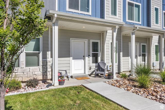 view of exterior entry with a porch and stone siding
