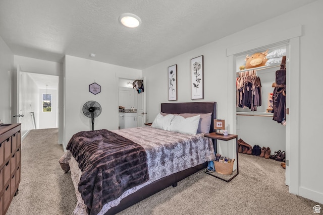 carpeted bedroom with a spacious closet, a textured ceiling, and a closet