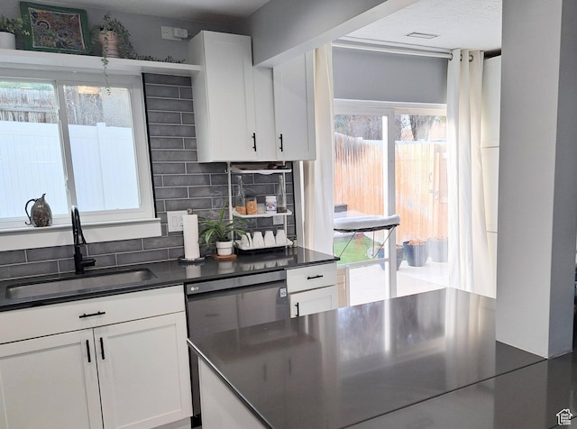 kitchen featuring a sink, decorative backsplash, dark countertops, and white cabinets