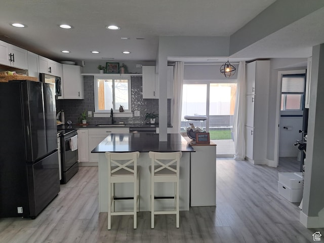 kitchen with dark countertops, a wealth of natural light, black appliances, and decorative backsplash