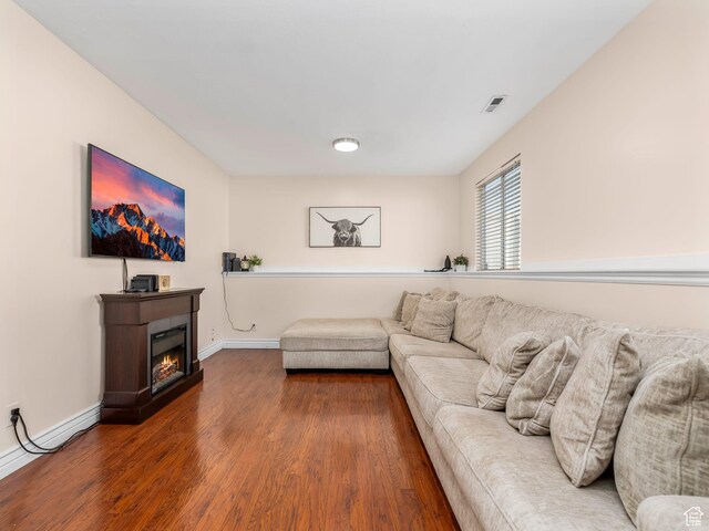 32 E Redwing Ct, Saratoga Springs, UT 84045 - living area featuring visible vents, baseboards, a lit fireplace, and dark wood-style floors