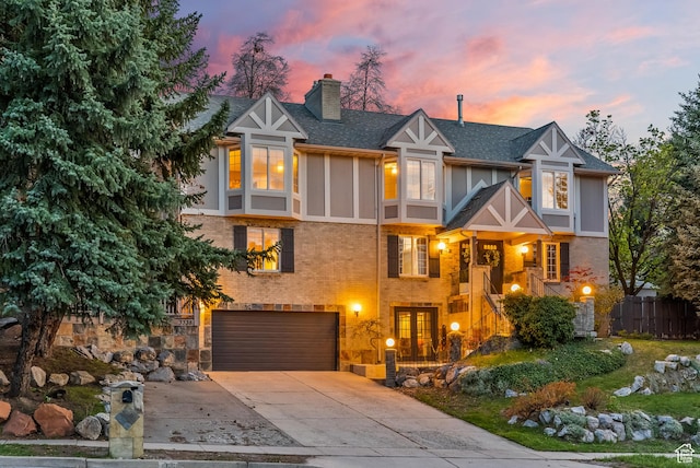 3338 E Creek Rd, Cottonwood Heights, UT 84121 - tudor home featuring driveway, an attached garage, a chimney, roof with shingles, and brick siding