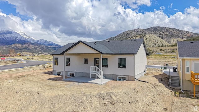 back of house with a patio, a mountain view, and a shingled roof