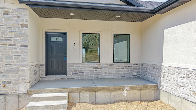 doorway to property featuring stucco siding and stone siding