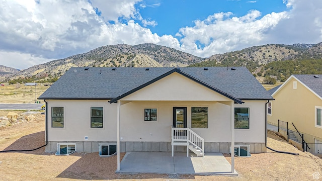 back of house with central AC, a mountain view, a shingled roof, a patio area, and stucco siding