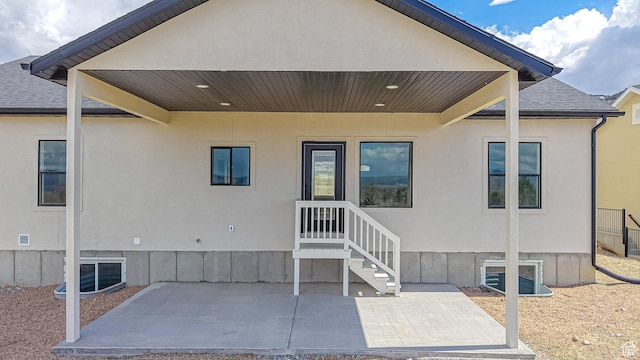 rear view of property featuring stucco siding, a patio, and roof with shingles