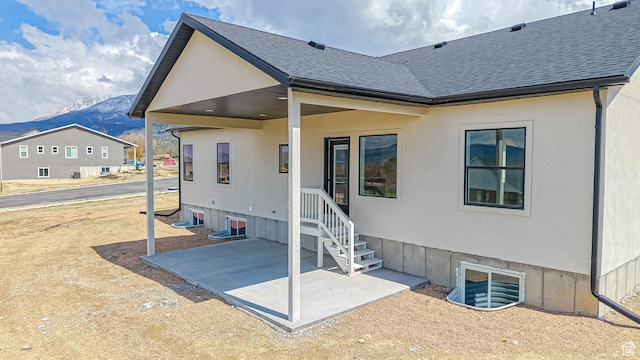 rear view of property featuring a patio area, roof with shingles, and a mountain view