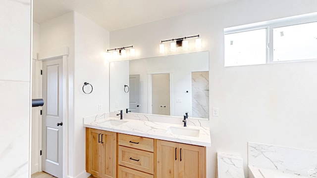 bathroom with double vanity, a bath, and a sink