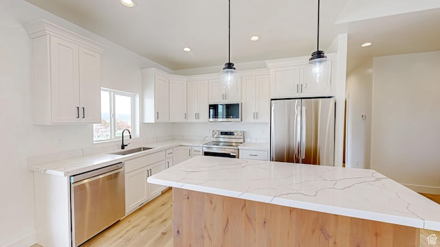 kitchen featuring stainless steel appliances, white cabinets, a sink, and light stone counters