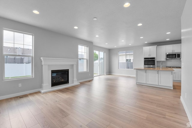 11888 S Golden Pine Ln, Riverton, UT 84065 - unfurnished living room with visible vents, recessed lighting, light wood-type flooring, and a glass covered fireplace