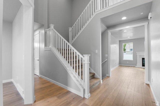 11888 S Golden Pine Ln, Riverton, UT 84065 - stairs featuring a glass covered fireplace, baseboards, recessed lighting, visible vents, and hardwood / wood-style floors