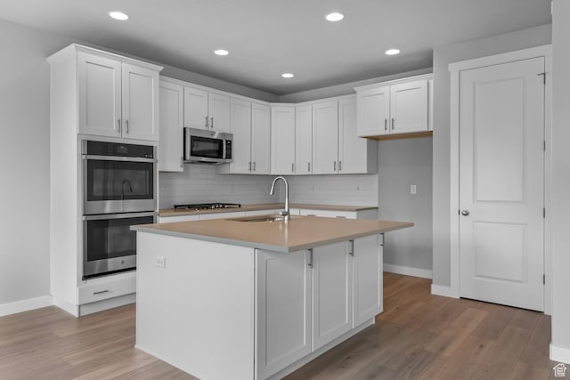 11888 S Golden Pine Ln, Riverton, UT 84065 - kitchen featuring stainless steel appliances, light wood-style flooring, white cabinetry, and decorative backsplash