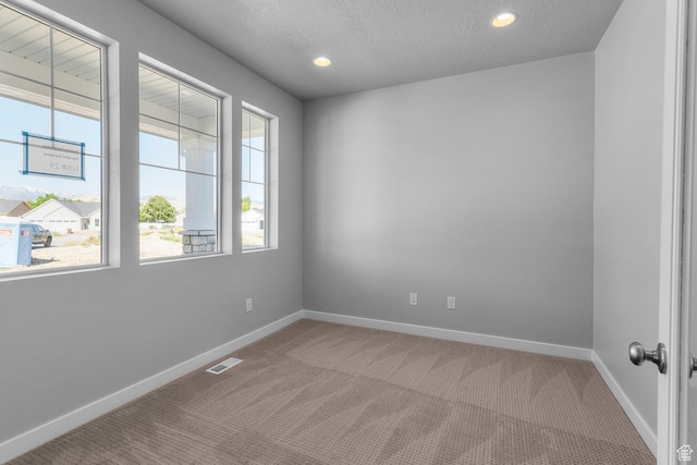 spare room featuring a textured ceiling, visible vents, recessed lighting, carpet floors, and baseboards
