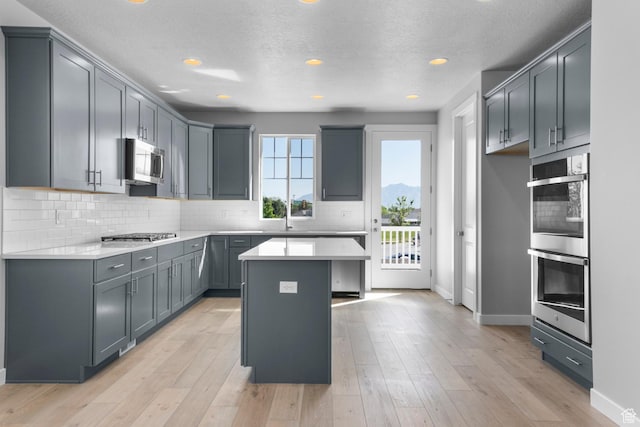 kitchen with backsplash, light countertops, light wood finished floors, and stainless steel appliances