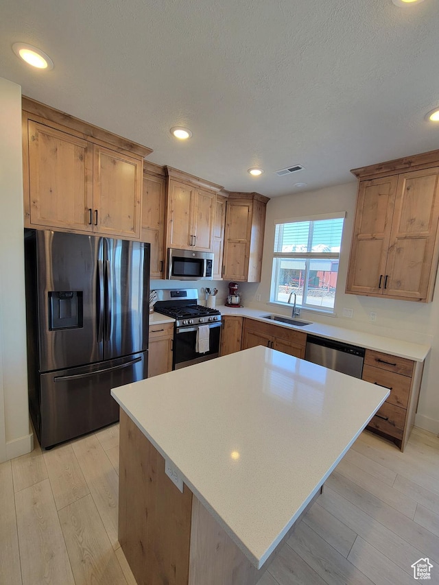 kitchen with light wood-type flooring, recessed lighting, light countertops, stainless steel appliances, and a sink