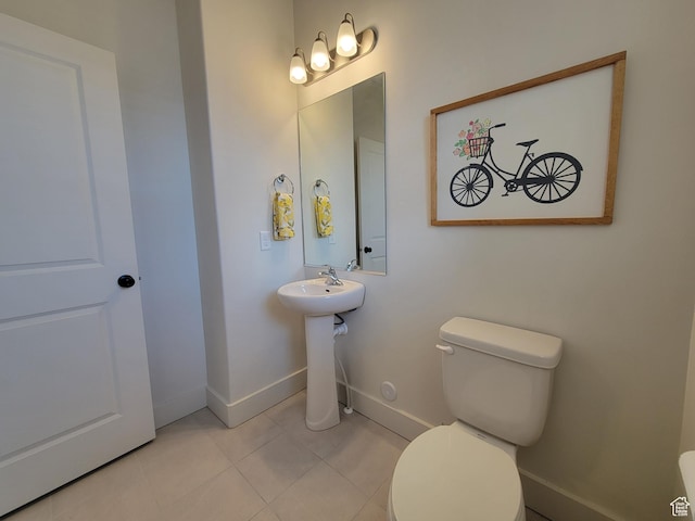 bathroom featuring tile patterned flooring, baseboards, a sink, and toilet