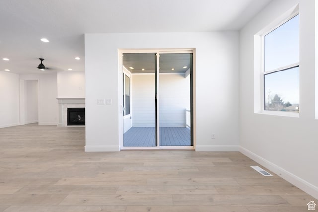 spare room featuring visible vents, baseboards, light wood-type flooring, a fireplace, and recessed lighting