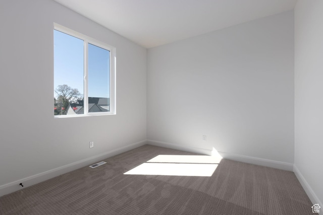 carpeted spare room with visible vents and baseboards