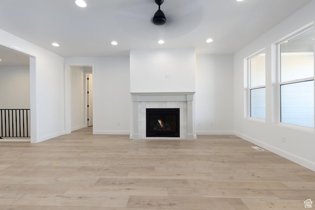 unfurnished living room featuring baseboards, ceiling fan, light wood-type flooring, a fireplace, and recessed lighting