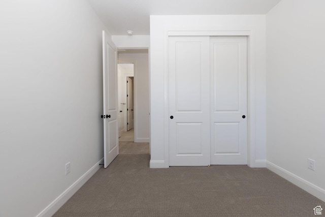 unfurnished bedroom featuring a closet, carpet flooring, and baseboards