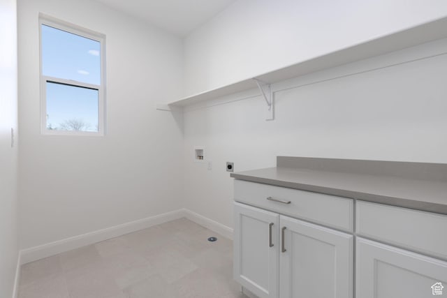 clothes washing area featuring electric dryer hookup, baseboards, light floors, washer hookup, and cabinet space