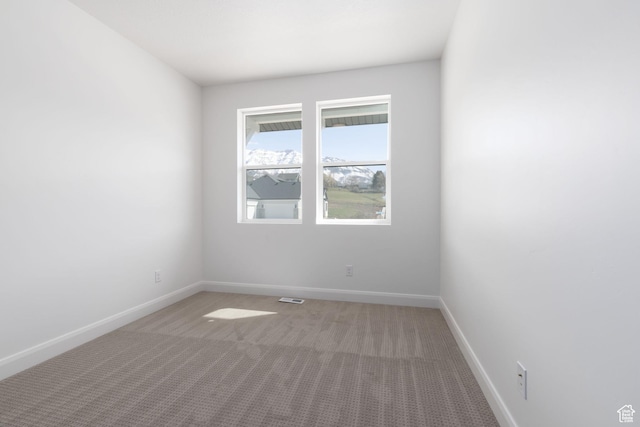 spare room featuring light colored carpet, baseboards, and visible vents