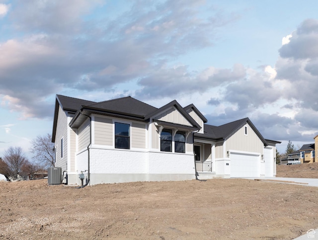 ranch-style house with central AC unit, a garage, board and batten siding, concrete driveway, and brick siding