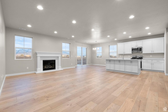 kitchen featuring recessed lighting, open floor plan, light wood-style flooring, white cabinets, and stainless steel appliances