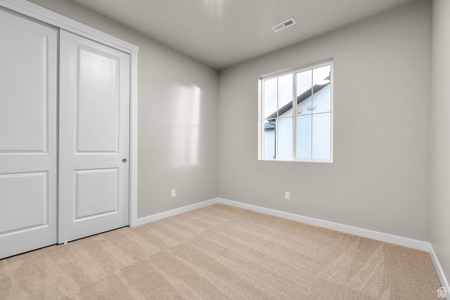unfurnished bedroom with a closet, baseboards, visible vents, and carpet floors