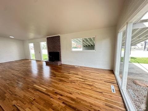 unfurnished living room with a brick fireplace and wood finished floors