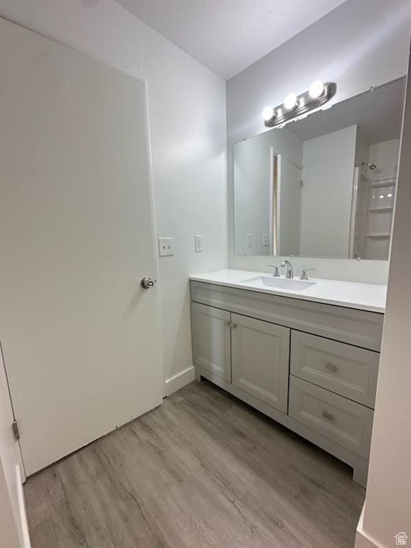 full bathroom with vanity, walk in shower, and wood finished floors