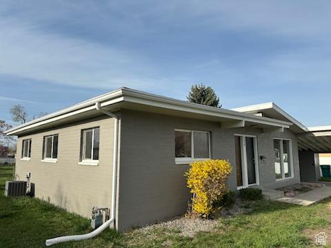 view of side of property with central AC unit and a lawn