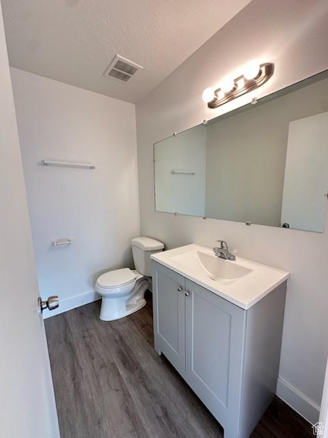 bathroom with visible vents, toilet, vanity, and wood finished floors