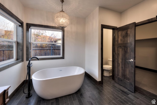 284 W Mcgill Blvd, Moab, UT 84532 - full bath featuring a soaking tub, an inviting chandelier, wood finish floors, toilet, and baseboards