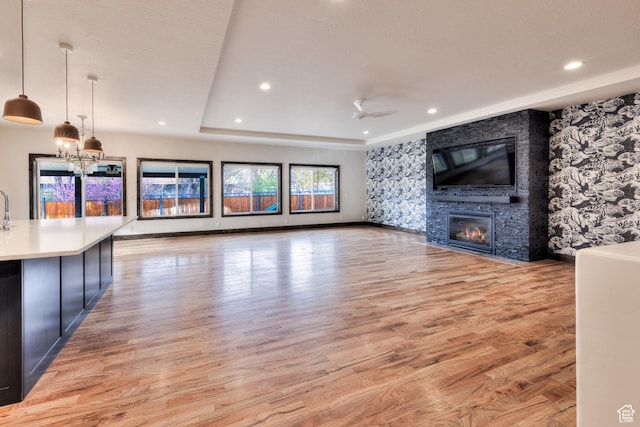 284 W Mcgill Blvd, Moab, UT 84532 - unfurnished living room featuring a large fireplace, recessed lighting, light wood-style floors, and ceiling fan with notable chandelier