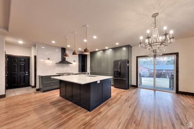 284 W Mcgill Blvd, Moab, UT 84532 - kitchen featuring black refrigerator with ice dispenser, a sink, wall chimney range hood, light countertops, and decorative backsplash