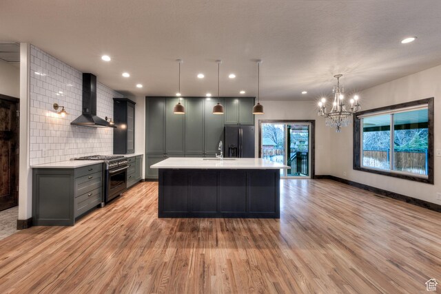 284 W Mcgill Blvd, Moab, UT 84532 - kitchen with wall chimney range hood, black fridge, stainless steel stove, light countertops, and backsplash