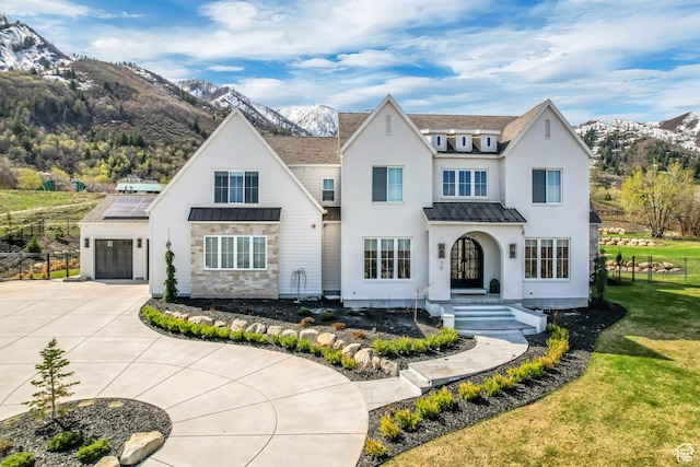 view of front facade featuring concrete driveway, a standing seam roof, metal roof, and a mountain view