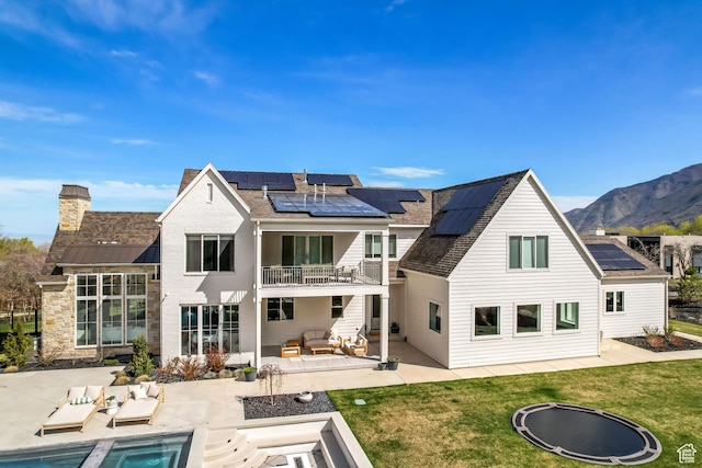 70 E Deer Meadow Ct, Woodland Hills, UT 84653 - back of house with a patio area, a balcony, a chimney, roof mounted solar panels, and an outdoor living space with a fire pit