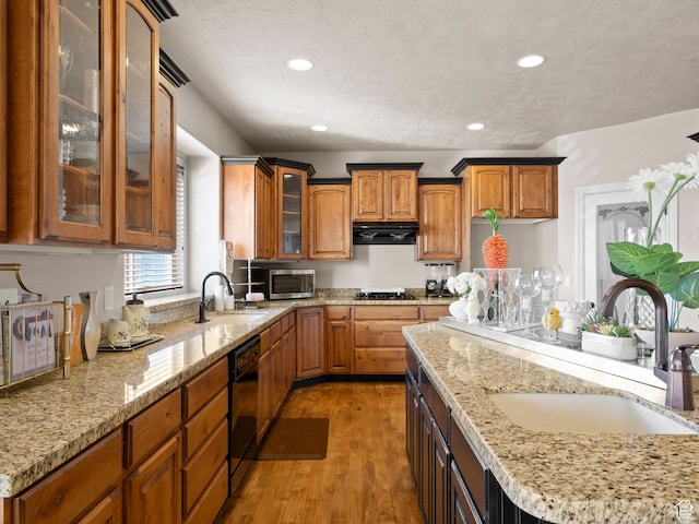 kitchen featuring stainless steel microwave, range hood, a sink, and black dishwasher