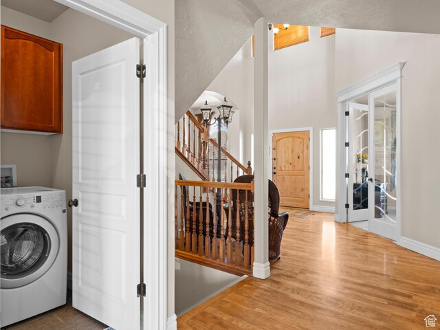 clothes washing area with wood finished floors, baseboards, cabinet space, and washer / dryer